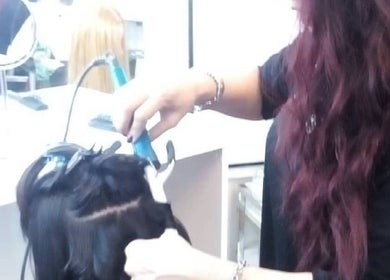 Estilista de V&L Beauty Studio en Ituzaingó aplicando rizador en cabello femenino.