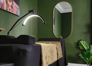 Cozy treatment room at Tati Beauty, Manchester, England, GB featuring green walls and modern decor.