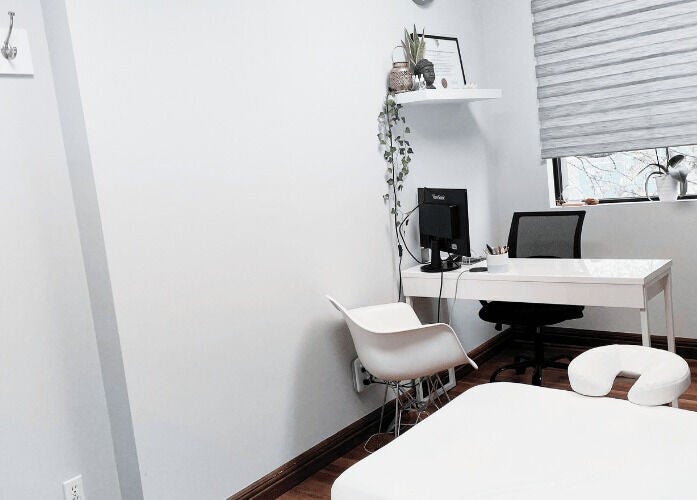 Bright therapy room at NB Ostéo/Kin, Laval, Québec, CA with massage table, desk, and chair.