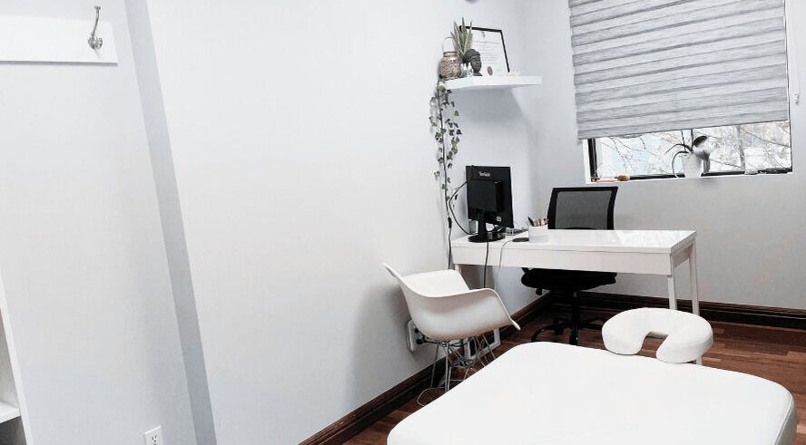 Bright therapy room at NB Ostéo/Kin, Laval, Québec, CA with massage table, desk, and chair.