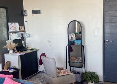 Interior view of Yeu’s Sisterlocs in Kempton Park, Gauteng, ZA, featuring a cozy styling area with a mirror and chair.