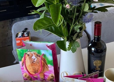 Yeu’s Sisterlocs in Kempton Park, Gauteng, ZA showcases a stylish table with flowers, wine, and a playful gift bag.