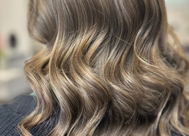 Elegant wavy hairstyle at Vikki’s Hair in Appledore, England, GB highlights glossy golden hues.