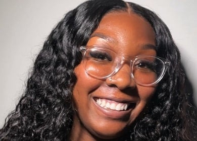 Happy woman with curly hair and glasses at Quori B. Aesthetics, Louisville, Kentucky, US.
