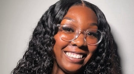 Happy woman with curly hair and glasses at Quori B. Aesthetics, Louisville, Kentucky, US.