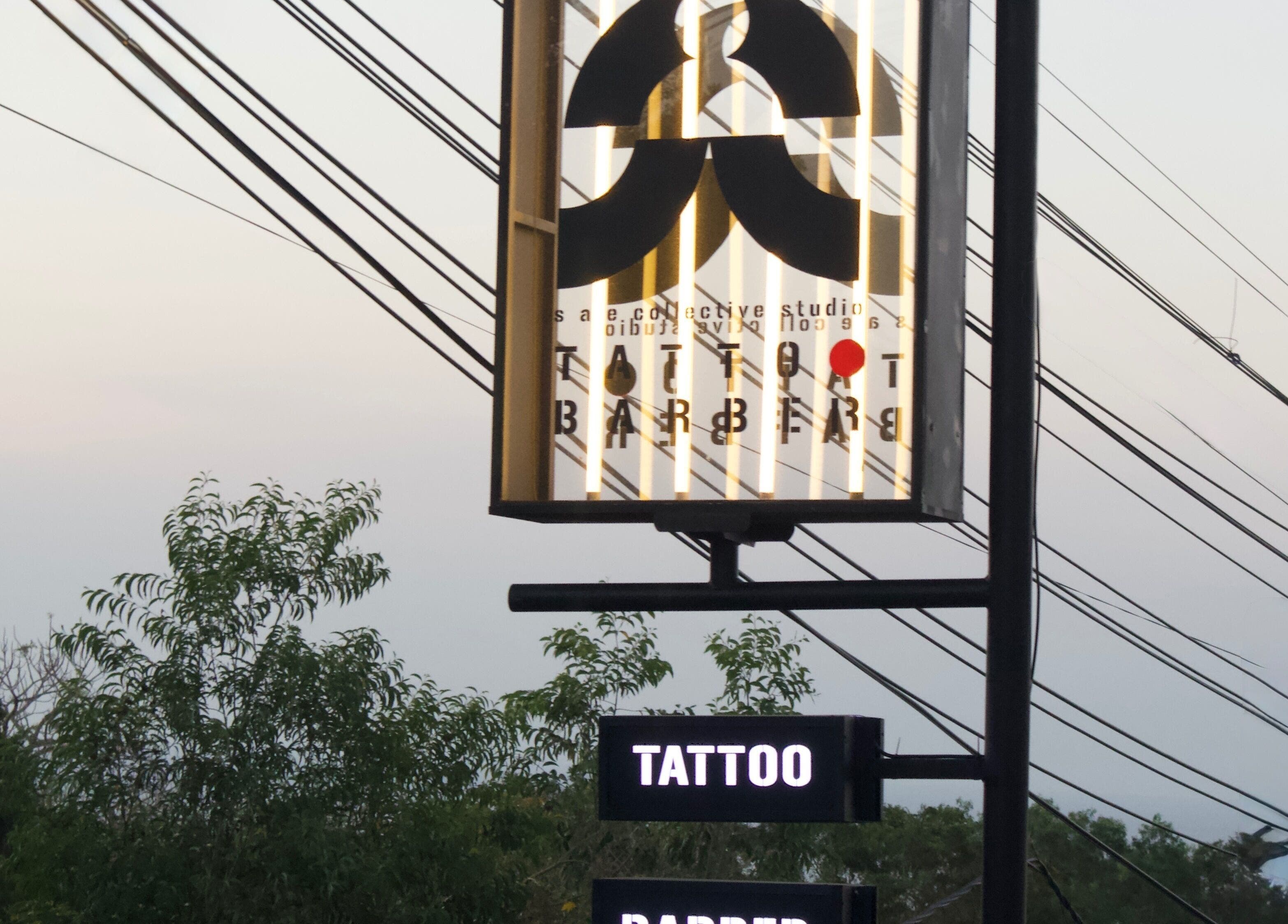 Illuminated Sae Collective Barber sign with trees in Bali, Bali, ID during dusk.