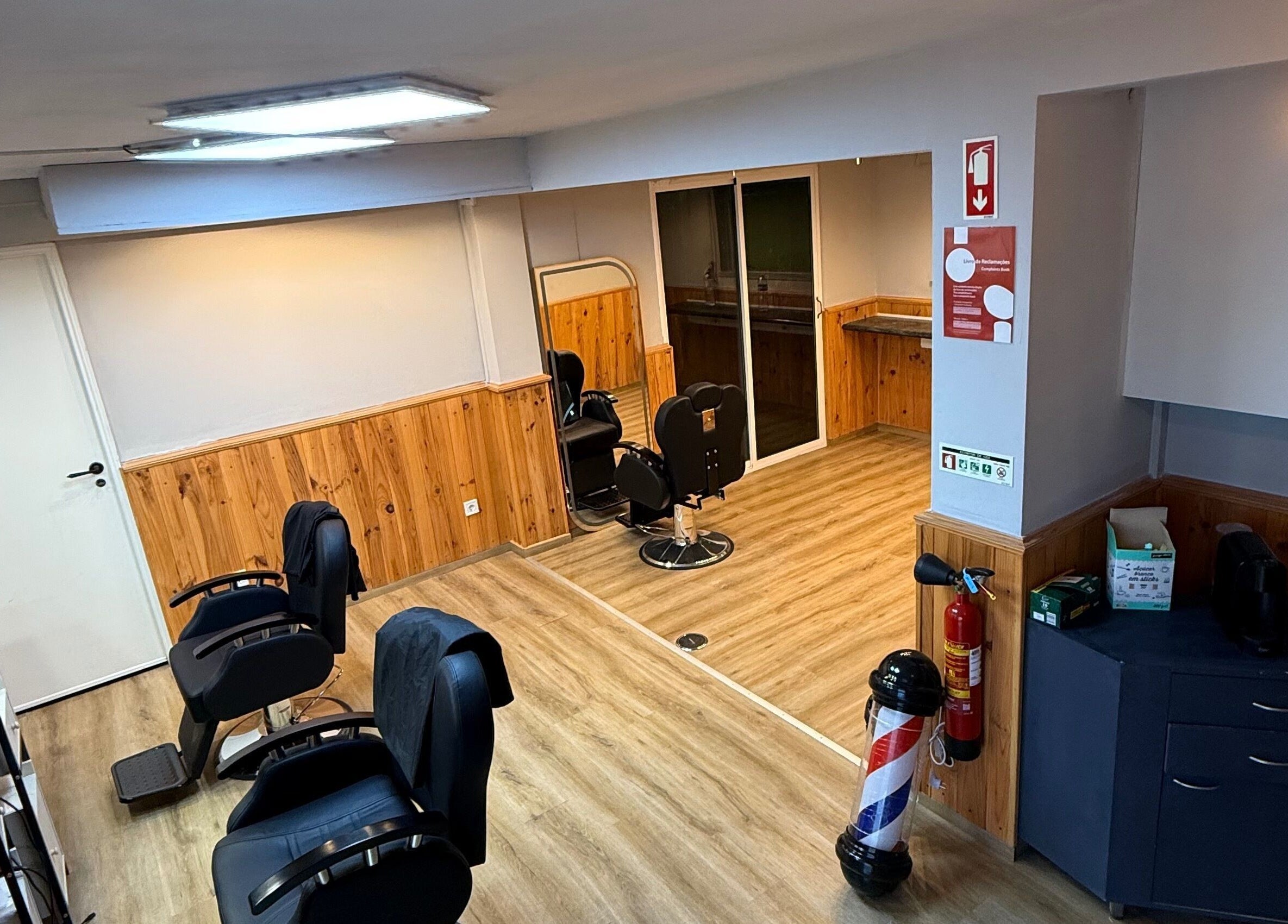 Interior moderno do Connect cut Barbers em Lisboa, PT, com cadeiras elegantes e decoração em madeira.