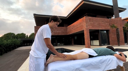 Terapista en Kirozurera Viladecans, Catalunya, ES da masaje al aire libre junto a una piscina.
