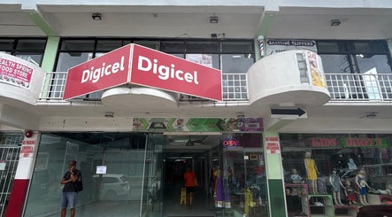 Entrance to Ariacrylics in Arima, Arima Borough Corporation, TT, featuring vibrant storefronts.