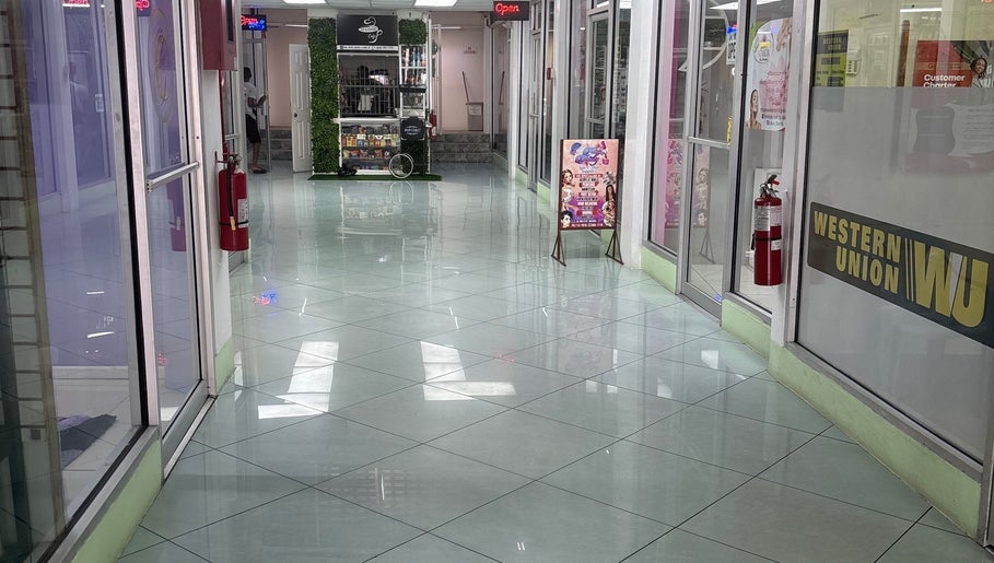 Entrance corridor of Ariacrylics in Arima Borough Corporation, TT with glass storefronts and signs.