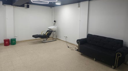 Sala de estética en PEAKY SHADES Bogotá, Bogotá, CO, con sillón negro y silla de lavado.