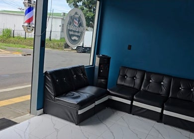 Comfortable seating at Mercedes Barber Shop, Barva, Heredia, CR, featuring stylish black sofas.