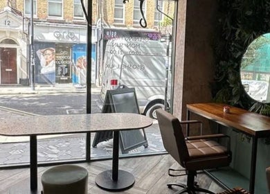 Relaxing interior of Na.Ko Hair London, featuring stylish furniture and green accents in London, England, GB.