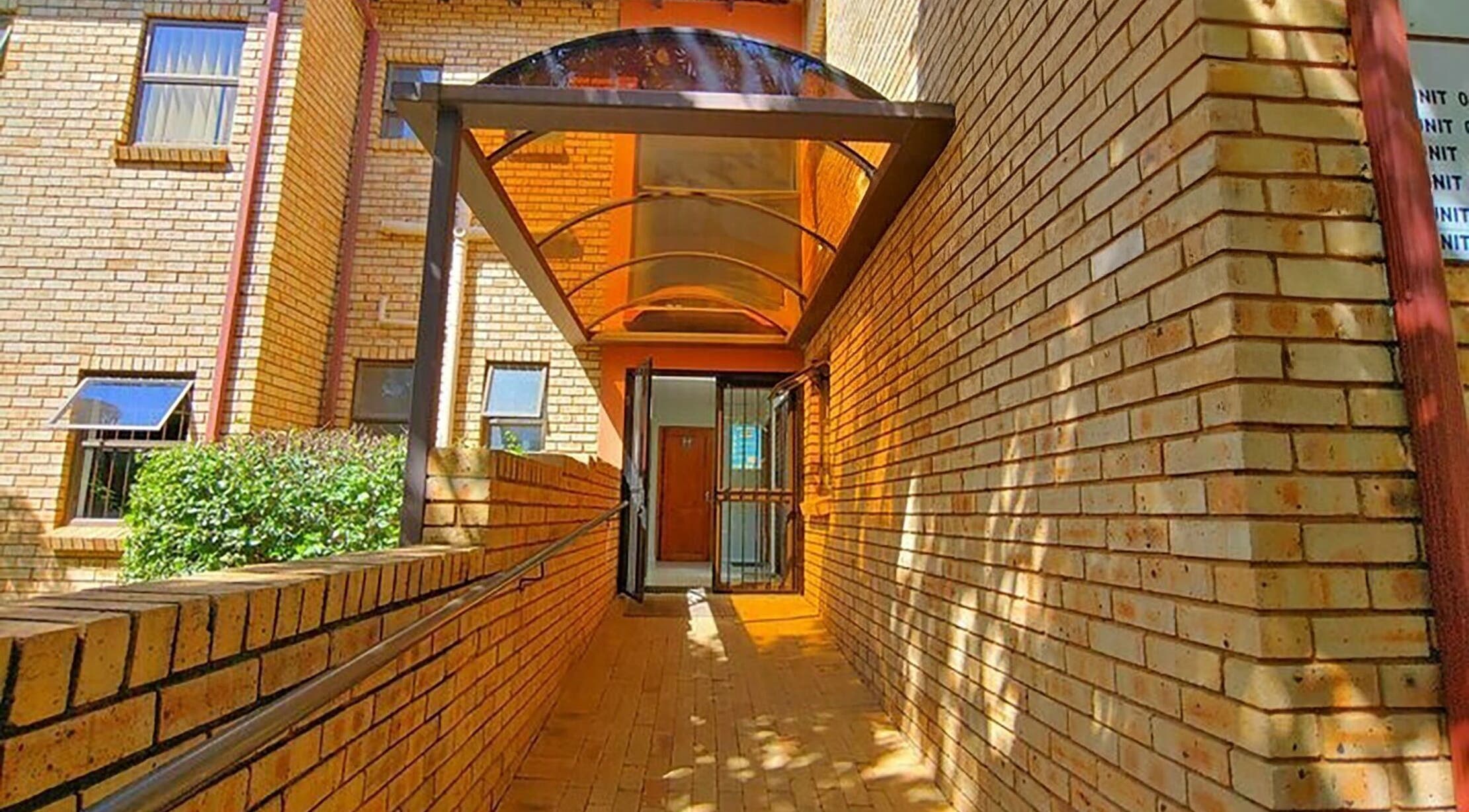 Entrance walkway to Brilliz Salon in Johannesburg, Gauteng, ZA with a sunlit brick passage.
