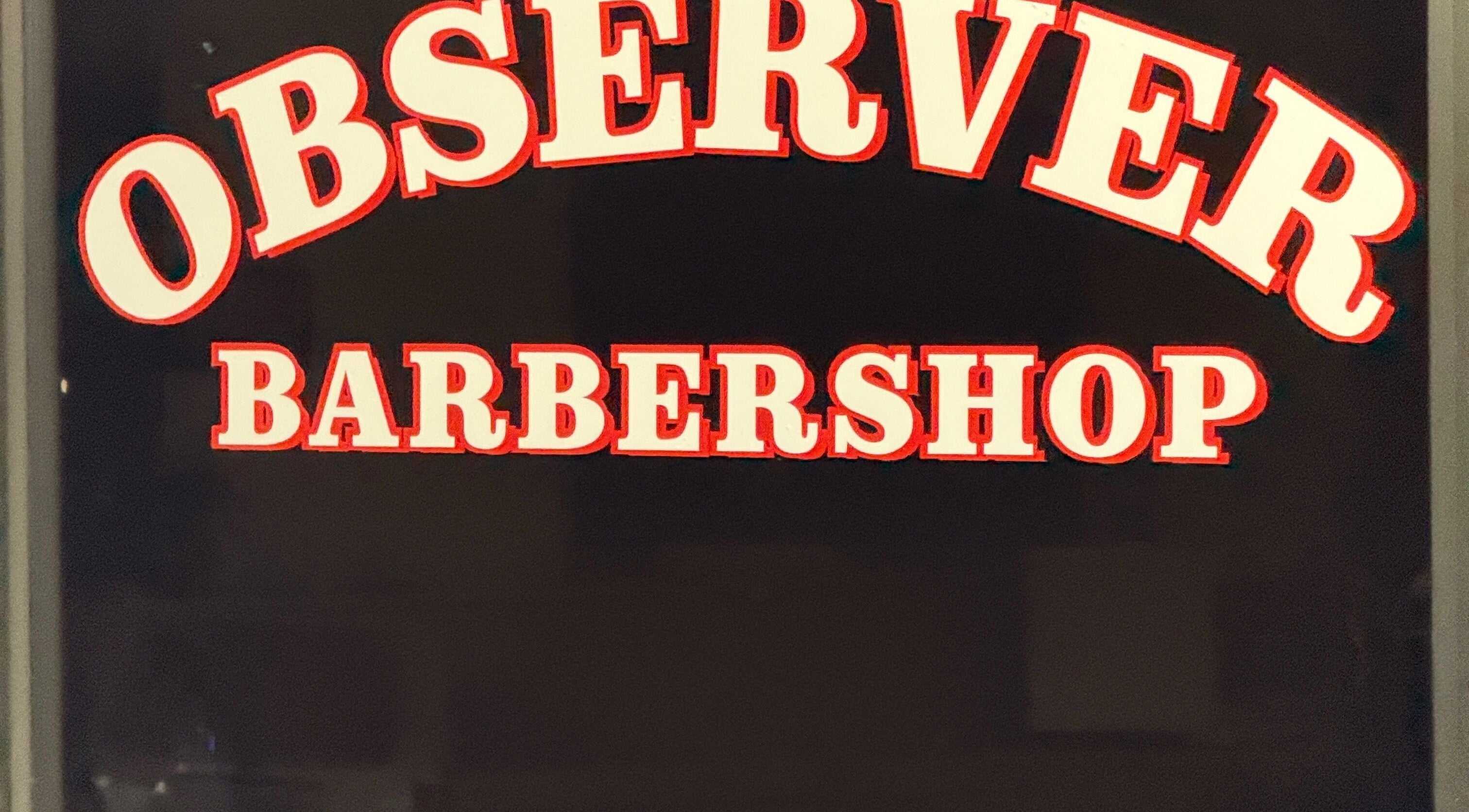 Sign for the Observer Barbershop in Beaverton, Oregon, US, displaying the name in bold red and white letters.