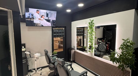 Interior elegante de EME BARBER STUDIO en Zaragoza, Aragón, ES con sillas y espejo iluminado.
