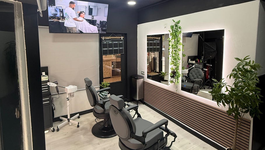 Interior moderno de EME BARBER STUDIO, Zaragoza, Aragón, ES, con sillas de barbería y espejo iluminado.