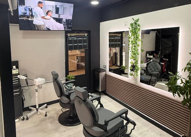 Interior moderno de EME BARBER STUDIO, Zaragoza, Aragón, ES, con sillas de barbería y espejo iluminado.