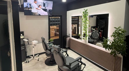 Interior moderno de EME BARBER STUDIO, Zaragoza, Aragón, ES, con sillas de barbería y espejo iluminado.