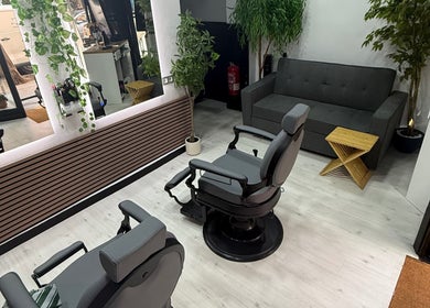 Interior moderno de EME BARBER STUDIO en Zaragoza, Aragón, ES con sillas de barbero y plantas decorativas.