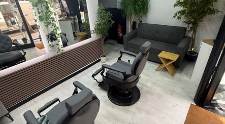 Interior moderno de EME BARBER STUDIO en Zaragoza, Aragón, ES con sillas de barbero y plantas decorativas.