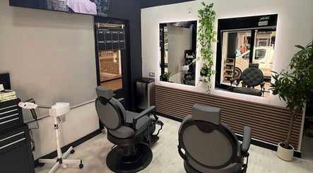 Interior moderno de EME BARBER STUDIO en Zaragoza, Aragón, ES, con sillones de barbero y plantas decorativas.