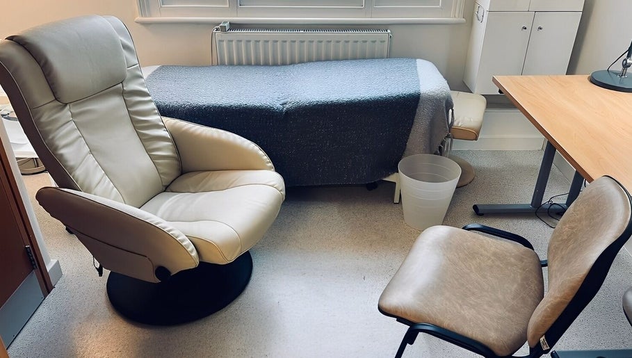 Cozy therapy room at Jenni Moresco Therapy in Baldock, England, featuring comfortable chairs and a therapy bed.