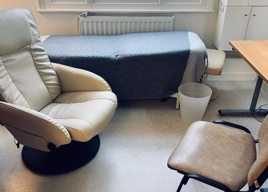 Cozy therapy room at Jenni Moresco Therapy in Baldock, England, featuring comfortable chairs and a therapy bed.