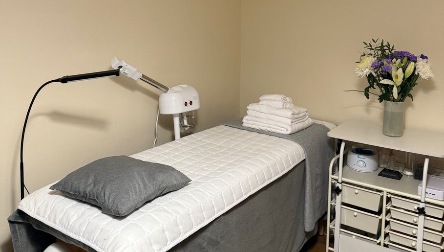 Treatment room with bed and flowers at Faya Beauty Studio, London, England, GB offering a calming ambiance.