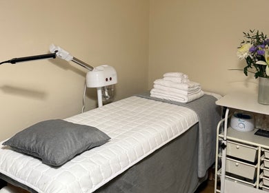 Treatment room with bed and flowers at Faya Beauty Studio, London, England, GB offering a calming ambiance.