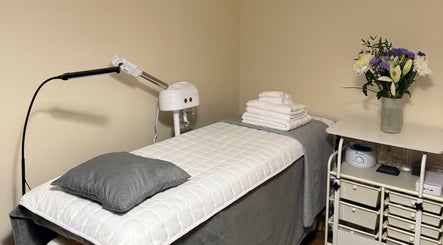 Treatment room with bed and flowers at Faya Beauty Studio, London, England, GB offering a calming ambiance.