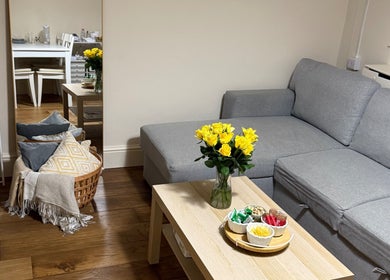 Cozy lounge area at Faya Beauty Studio, London, England, GB with sofa, yellow roses, and snacks on table.