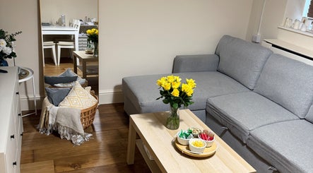 Cozy lounge area at Faya Beauty Studio, London, England, GB with sofa, yellow roses, and snacks on table.