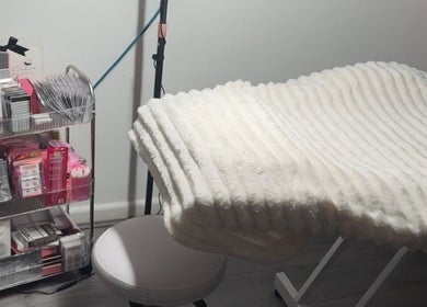 Comfortable eyelash treatment bed at TheLashLab, Bettws, Wales, GB, surrounded by beauty supplies.