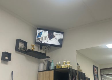 Intérieur moderne de Universal’s barber, Le Moule, Grande-terre, GP, avec étagères design et télévision.