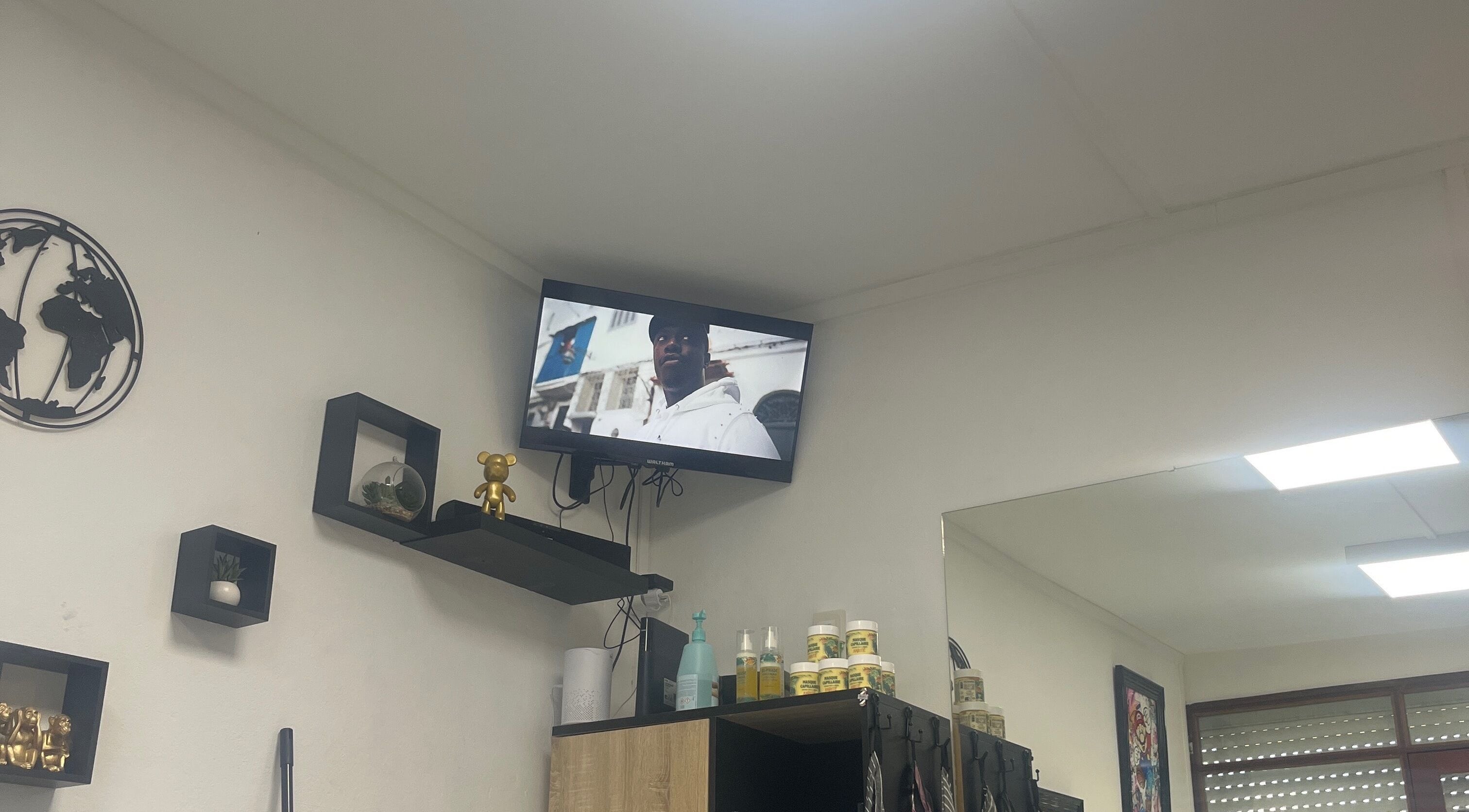 Intérieur moderne de Universal’s barber, Le Moule, Grande-terre, GP, avec étagères design et télévision.