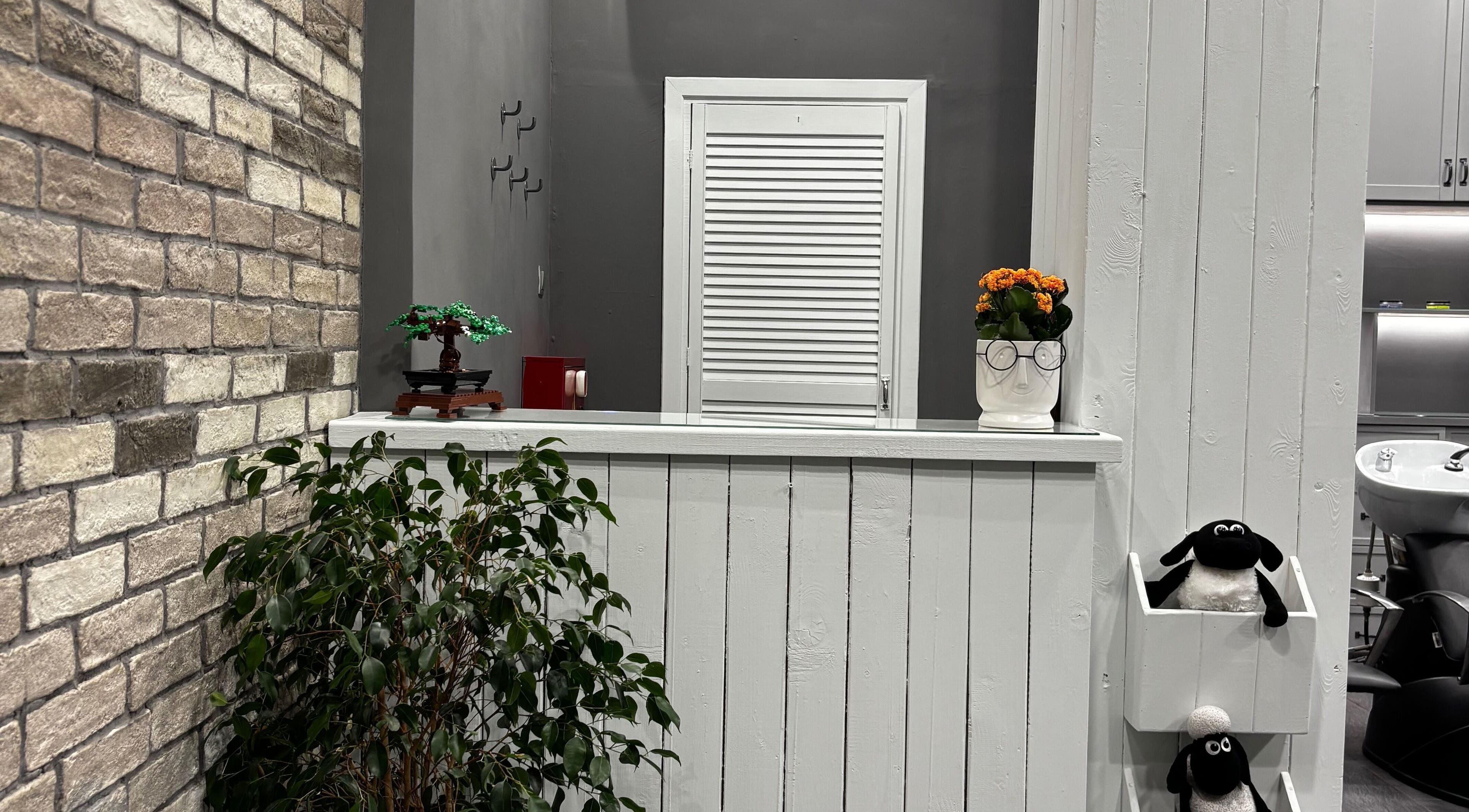 Κομψός χώρος υποδοχής στο Gossheep Barbershop, Θεσσαλονίκη, GR με φυτά και μοντέρνα διακόσμηση.