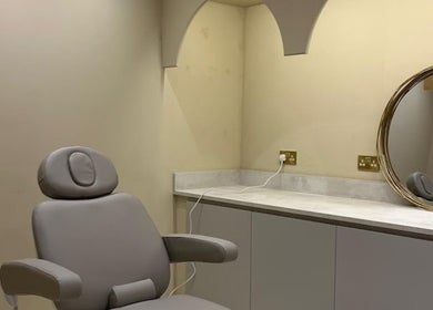 Modern treatment room at Dr Sophie Aesthetics in Clarkston, Scotland, GB with plush chair and decorative mirror.