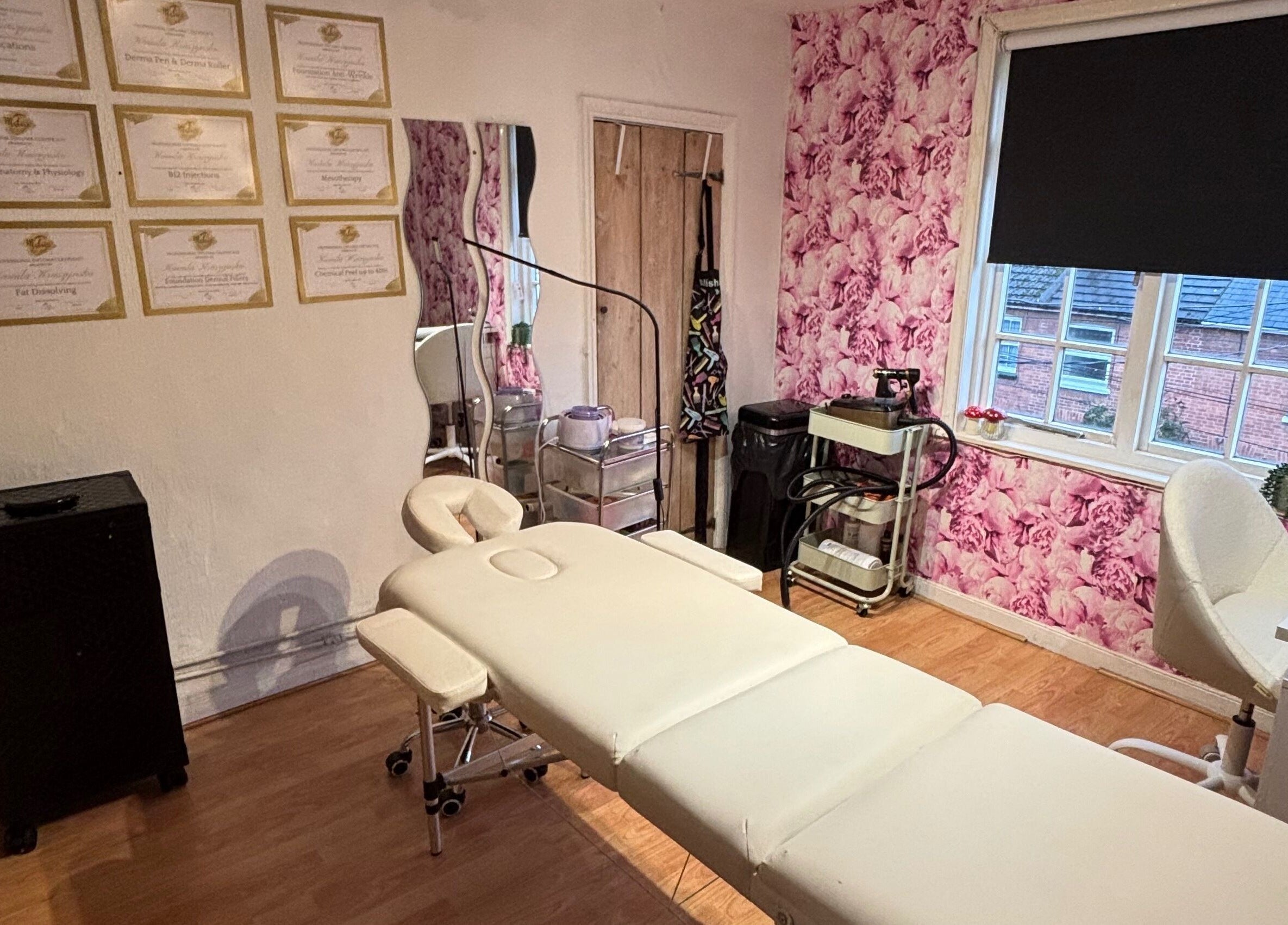 Treatment room at KK Aesthetic, Braintree, England, GB with floral wallpaper and a comfortable treatment bed.