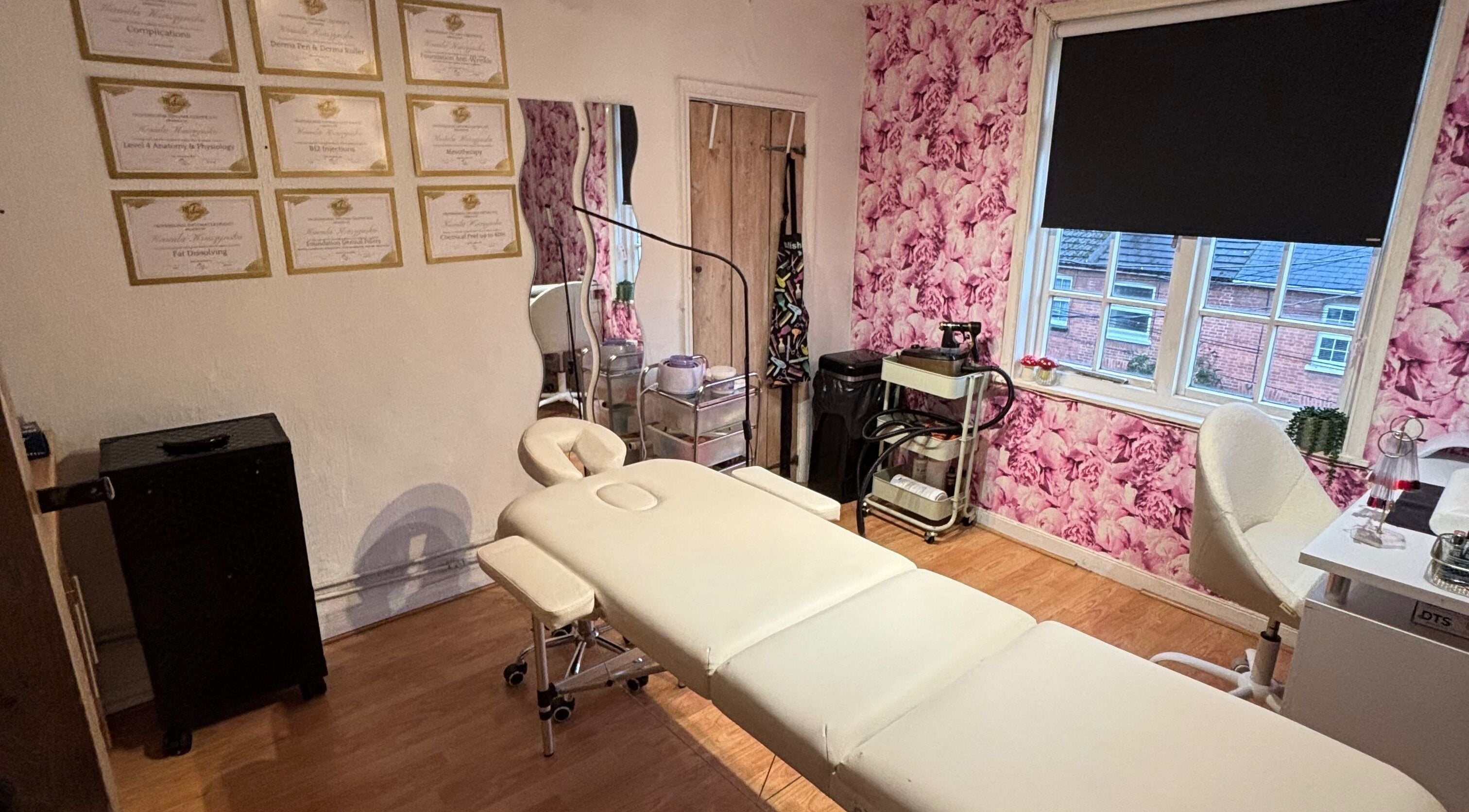 Treatment room at KK Aesthetic, Braintree, England, GB with floral wallpaper and a comfortable treatment bed.