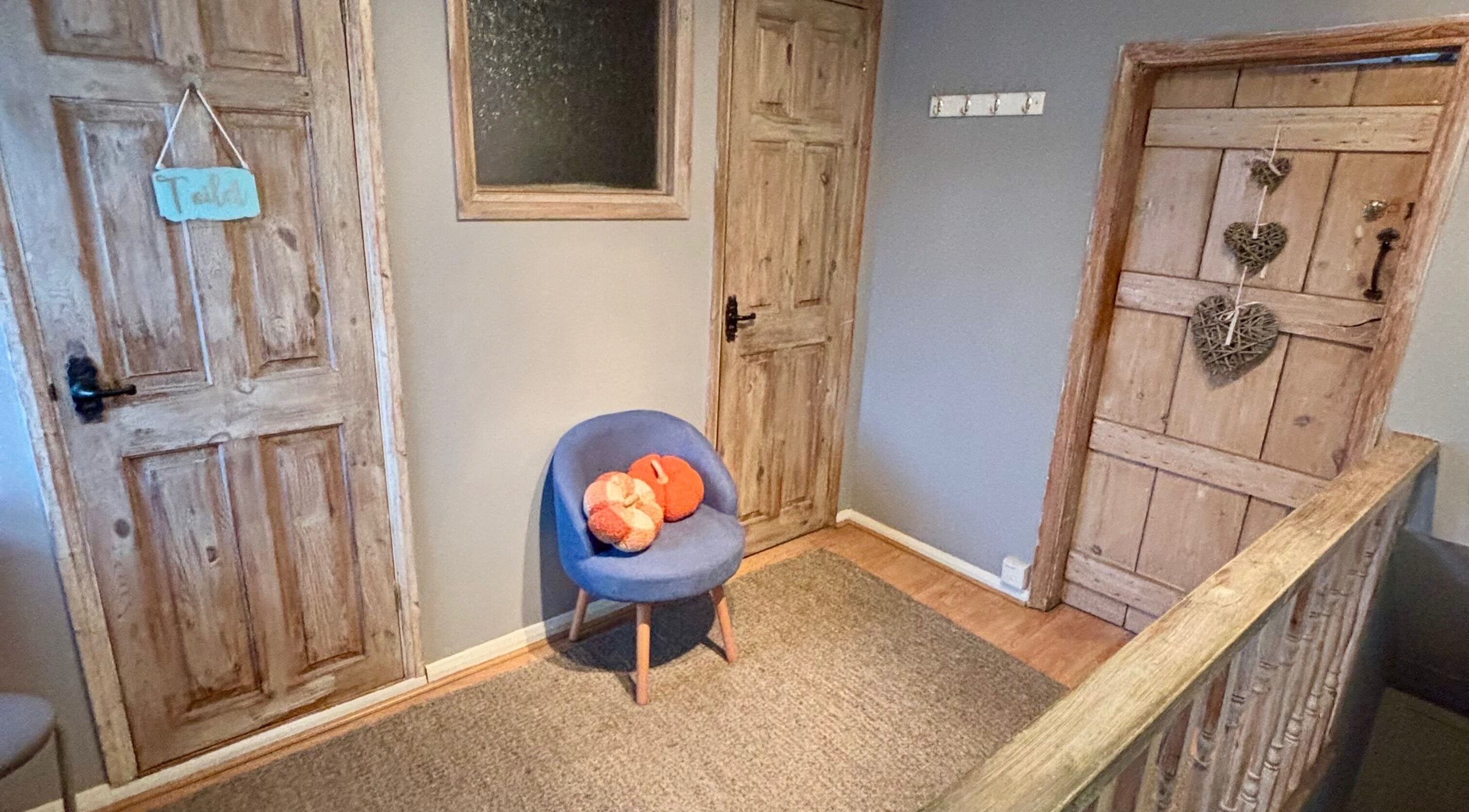 Cozy corner at KK Aesthetic in Braintree, England, GB with a rustic wooden door and a plush blue chair.
