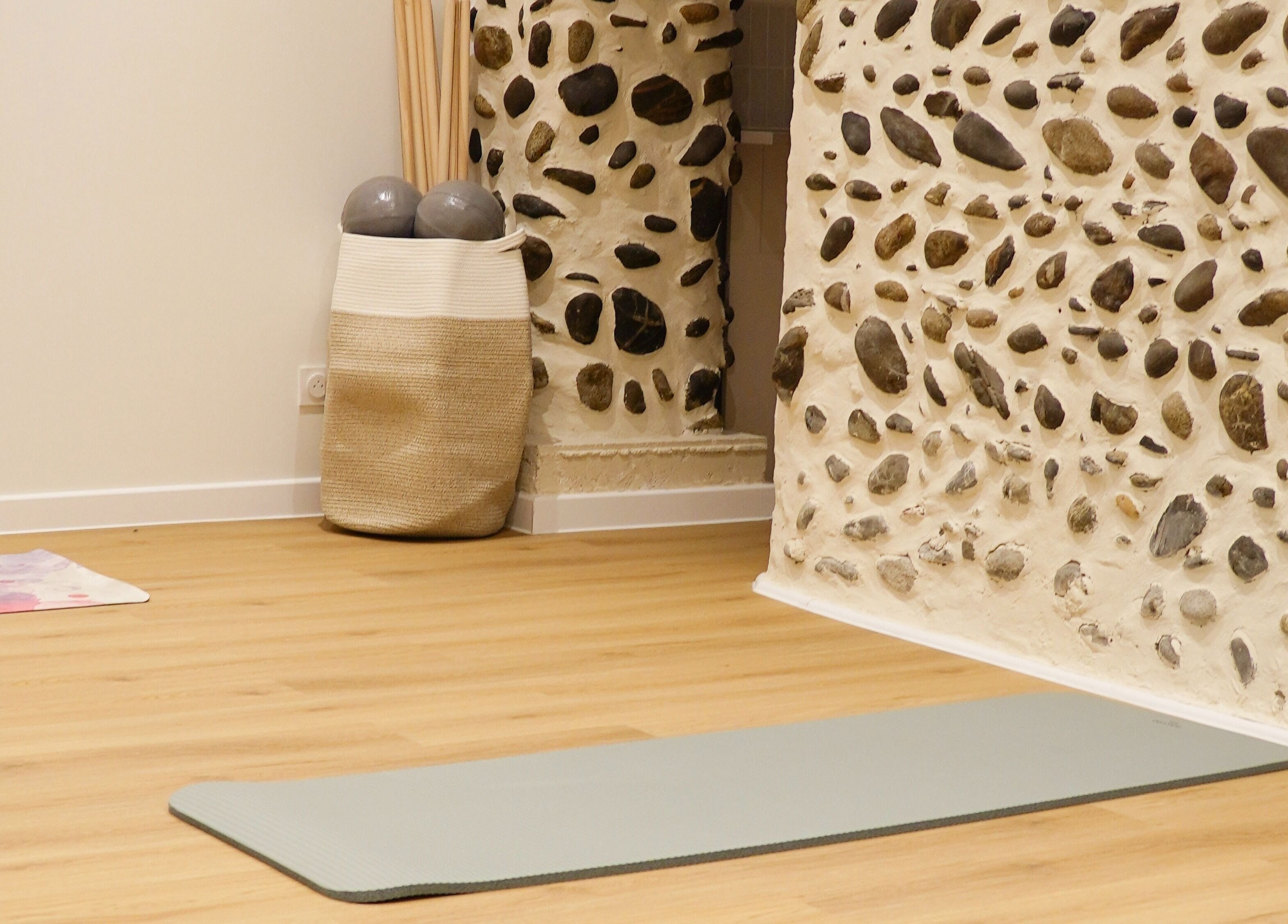 Espace de yoga paisible chez Le soin par Alexia, Pau, Nouvelle-Aquitaine, FR, avec tapis et mur en pierre.
