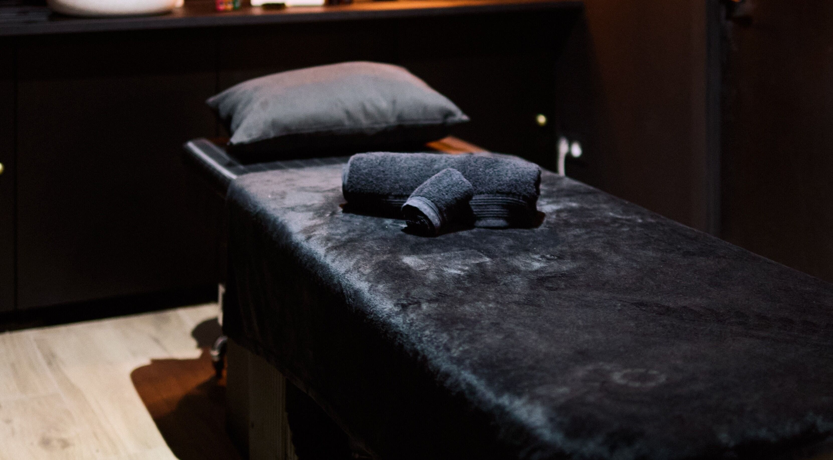 Cama de masaje en Nágar, Tetuán, Comunidad De Madrid, ES, con toallas negras elegantes.