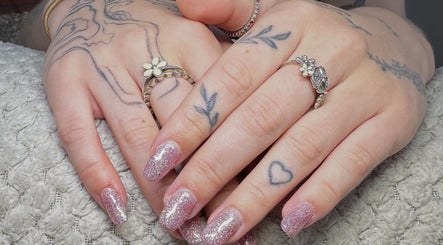 Sparkling glitter nails at Lluxury Nails, Weston-super-Mare, England, GB with delicate tattoo art and rings.
