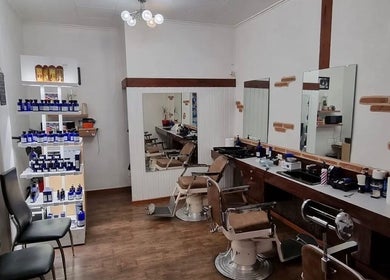 Intérieur moderne de Coiffure Men's à Genève, Genève, CH avec fauteuils de barbier et produits de soin.