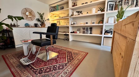Interieur van Irie Dreads Bonaire in Kralendijk, Bonaire, BQ met een stijlvolle kappersstoel en houten inrichting.