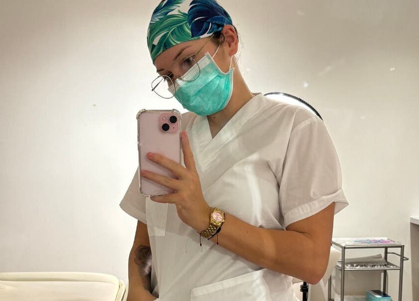 Aesthetician in uniform at Diamond M Aesthetics, Brighton and Hove, England, GB, taking a selfie.