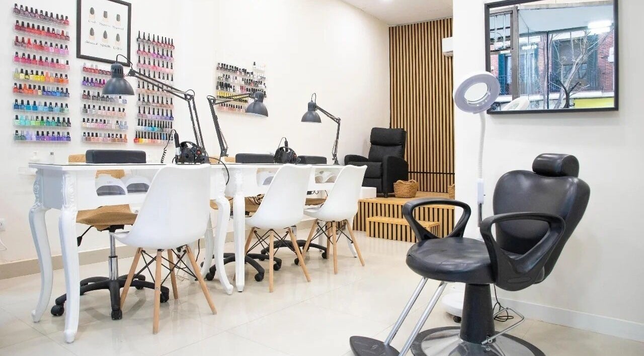 Espacio de manicura en Auri Salón, Madrid, Comunidad De Madrid, ES con sillas blancas y estantes de esmaltes.