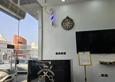 داخل Safety Scissors Barbershop بالرياض، SA بتصميم داخلي أنيق وساعة حائط كلاسيكية.
