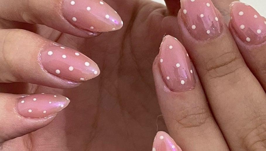 Uñas decoradas con esmalte rosa y puntos blancos en Afrodita Estética, Rosario, Santa Fe, AR.